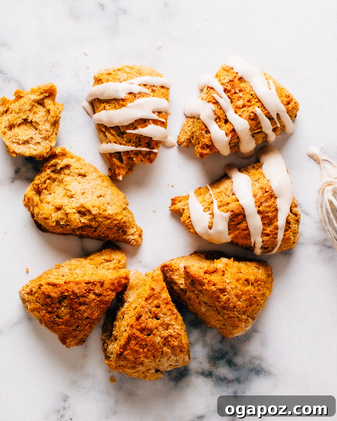 Overhead view of glazed and unglazed pumpkin scones on a marble counter.