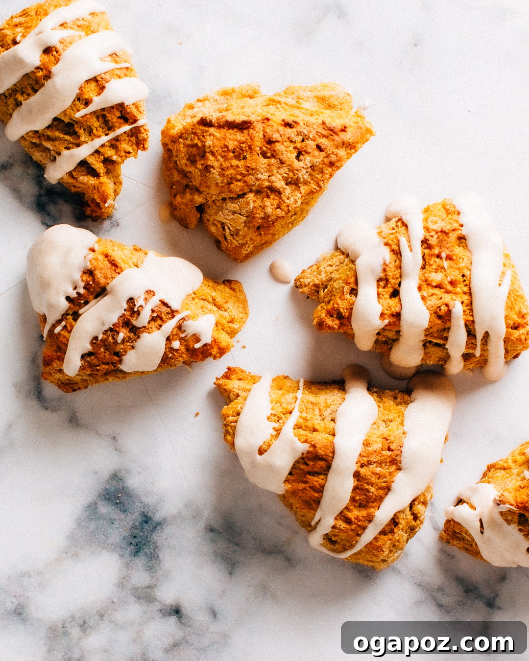 Pumpkin scones with cinnamon glaze on a marble surface.